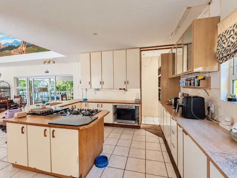 Spacious kitchen featuring built-in cabinetry, a gas hob, and tiled flooring, offering significant potential for modernization and renovation.