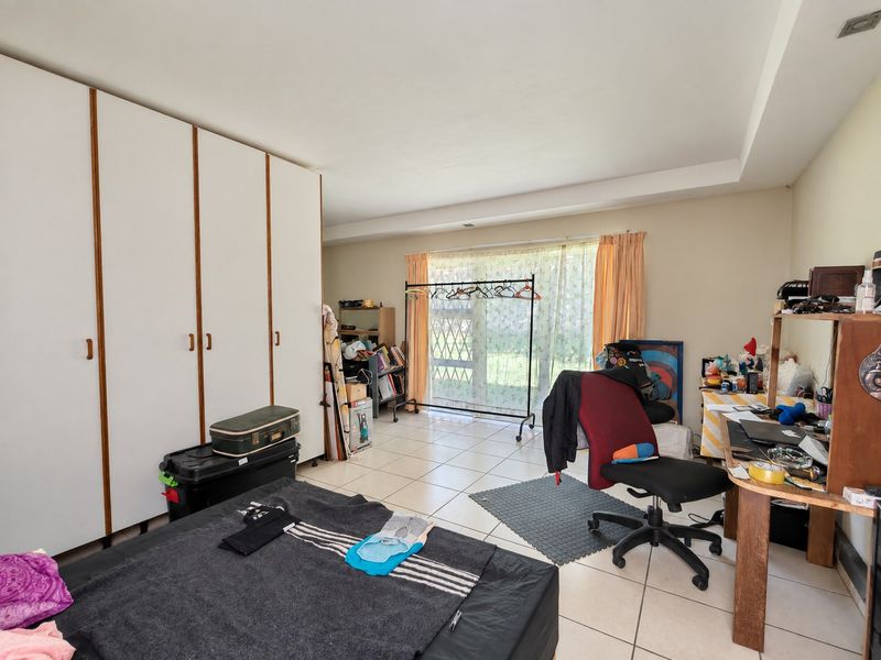 Spacious bedroom featuring large built-in cupboards, tiled flooring, and a sliding glass door providing natural light and garden access.