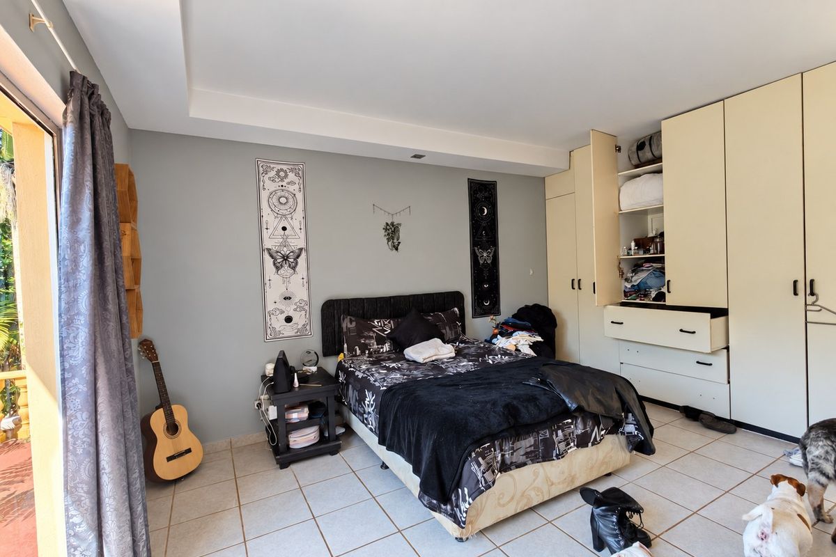 A bedroom featuring built-in cupboards, tiled flooring, and a sliding door providing access to an outdoor area.