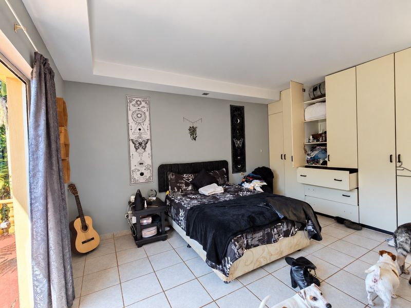 A bedroom featuring built-in cupboards, tiled flooring, and a sliding door providing access to an outdoor area.