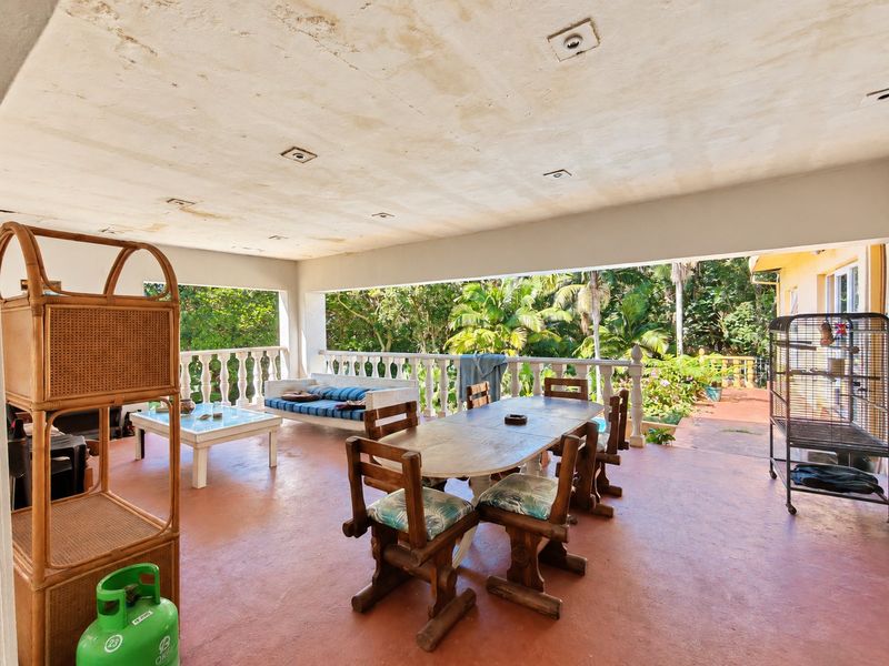 Spacious covered patio featuring a concrete floor, decorative balustrade, and recessed lighting, offering a view of the surrounding garden.