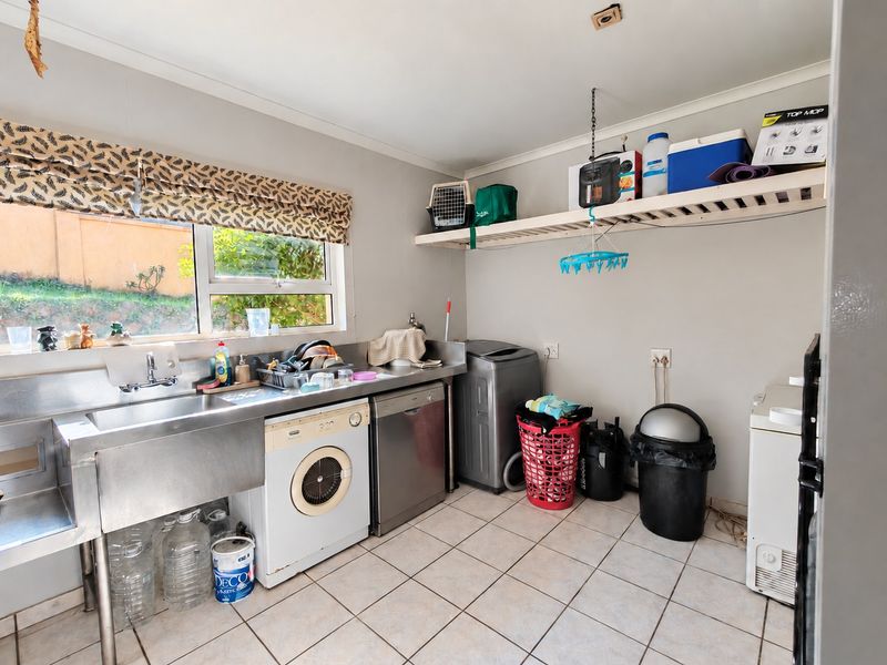 Functional laundry room featuring a stainless steel sink, tiled flooring, and wall-mounted storage shelving with space for appliances.