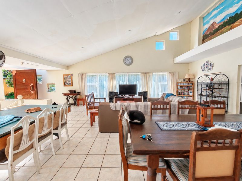Spacious open-plan living and dining area featuring vaulted ceilings, tiled flooring, and large sliding doors that provide ample natural light.