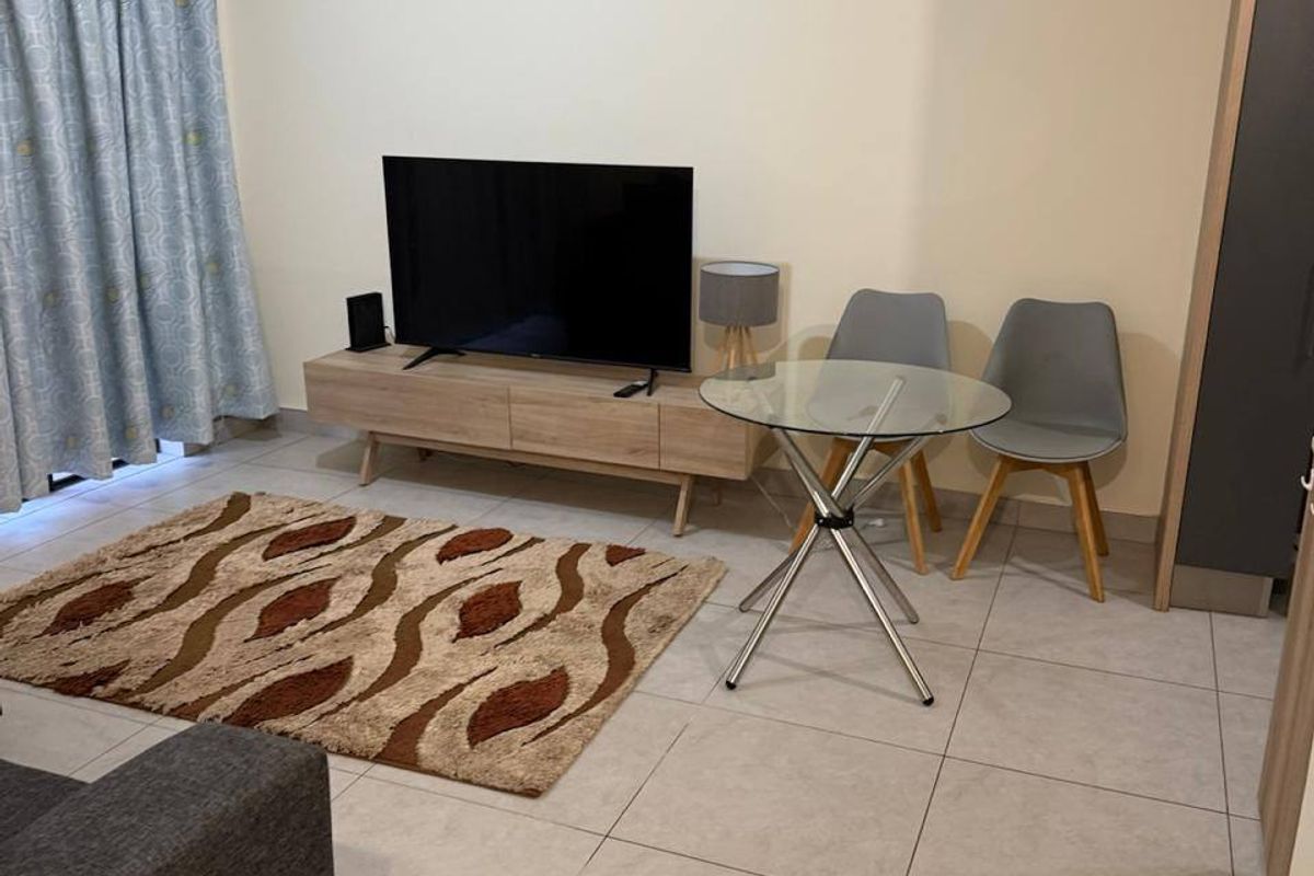 A functional living room featuring neutral tiled flooring and access to an outdoor area via a sliding door.