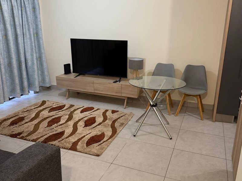 A functional living room featuring neutral tiled flooring and access to an outdoor area via a sliding door.