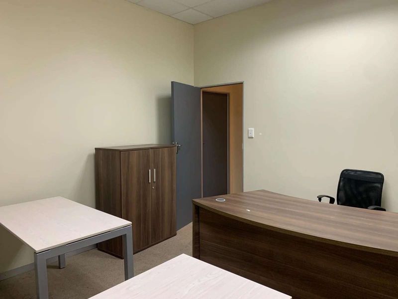 A functional office space featuring neutral wall finishes, carpeted flooring, and a suspended ceiling, providing a clean and professional work environment.