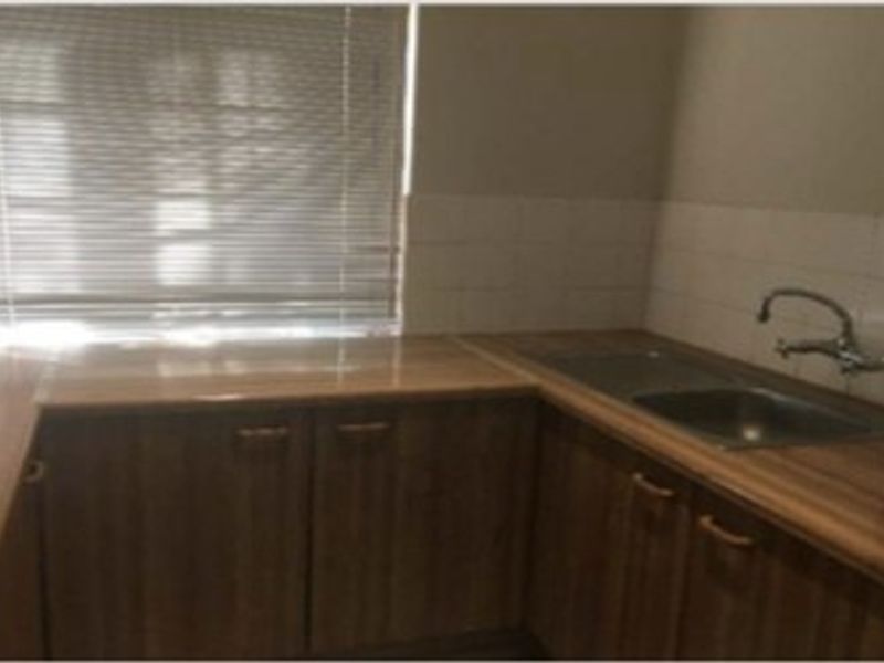 A functional kitchen area featuring laminate countertops, a double basin sink with mixer tap, and tiled splashbacks, providing a practical workspace.