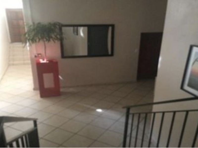 A spacious hallway area featuring tiled flooring and a metal staircase railing, providing access to multiple sections of the commercial property.