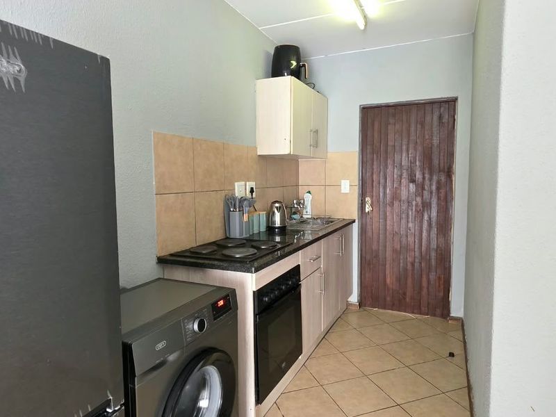 Compact kitchen featuring built-in cabinetry, electric hob, oven, and tiled backsplash, providing a functional workspace with tiled flooring.