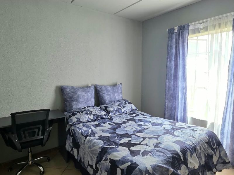 A functional bedroom featuring tiled flooring and a window with natural light, providing a comfortable space for rest.