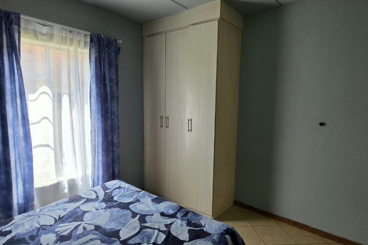 A bedroom featuring tiled flooring and a built-in wardrobe, providing functional storage space.