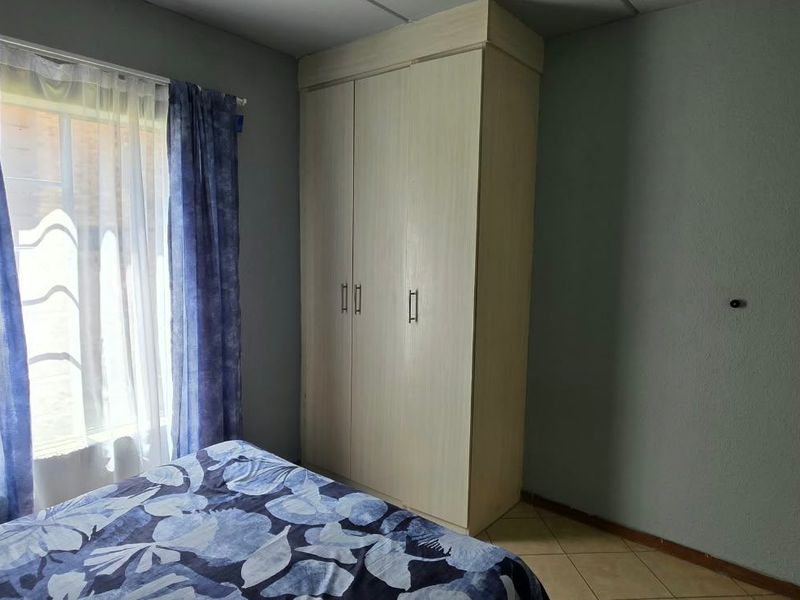 A bedroom featuring tiled flooring and a built-in wardrobe, providing functional storage space.