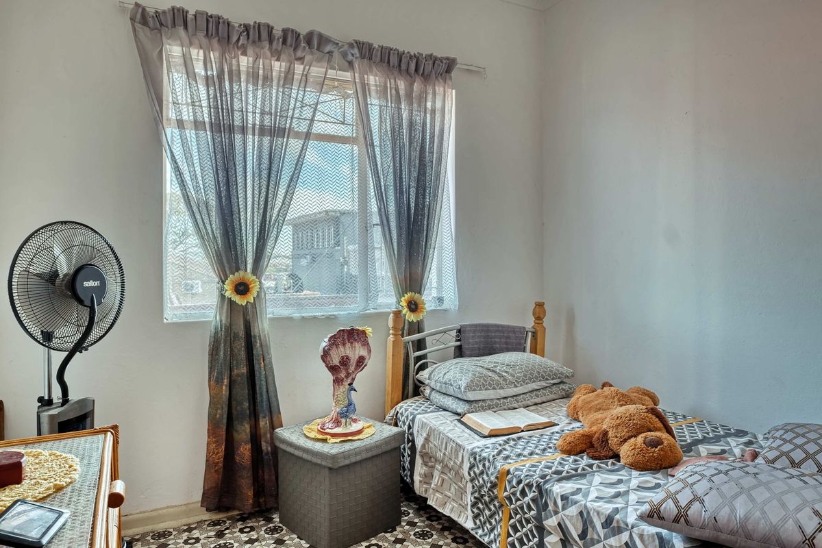 A functional bedroom featuring a window with curtain rod, providing natural light and a view of the exterior.