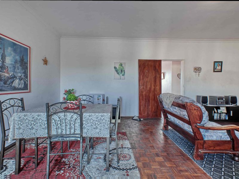 Open plan living and dining area featuring traditional parquet flooring and a wooden interior door.