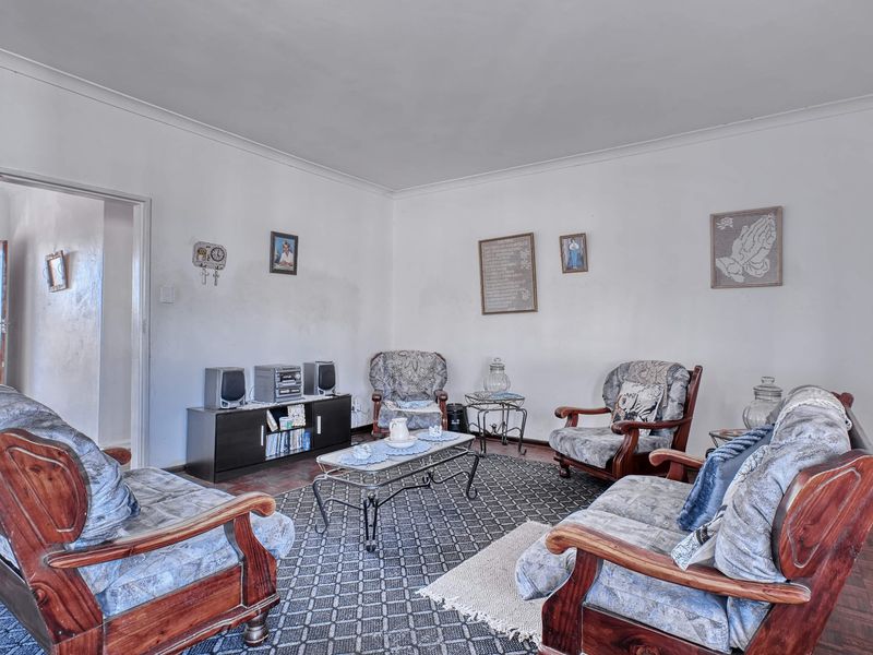 A living room featuring parquet flooring and coved ceilings, requiring cosmetic updates to the wall finishes to improve the overall aesthetic.