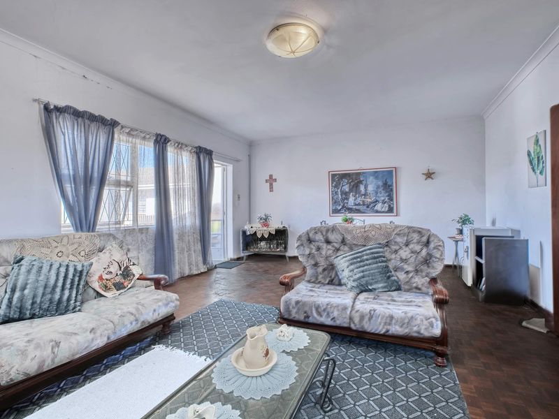 Spacious living room featuring traditional parquet flooring, coved ceilings, and large windows that provide natural light.
