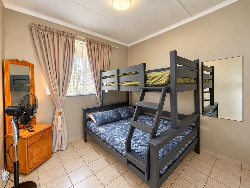 A functional bedroom featuring neutral wall tones, tiled flooring, and a wall-mounted mirror, providing a practical space for residents.