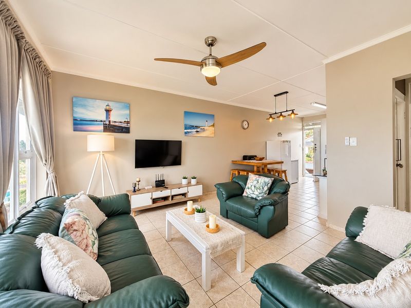 An open-plan living and dining area featuring tiled flooring, a ceiling fan, and neutral wall tones, providing a bright and functional living space.