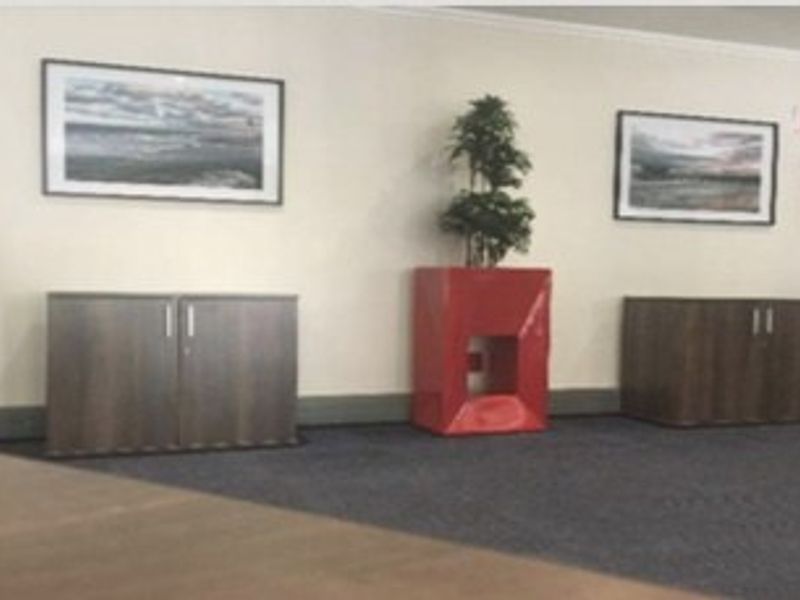 A commercial hallway featuring carpeted flooring, neutral walls, and a wall-mounted fire extinguisher.