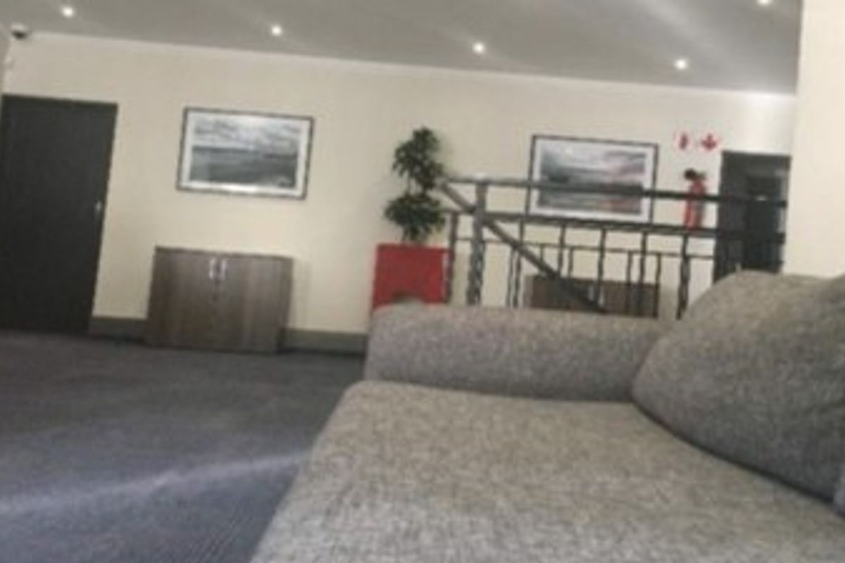 A commercial interior space featuring recessed downlighting, a metal balustrade, and carpeted flooring, suitable for a reception or waiting area.