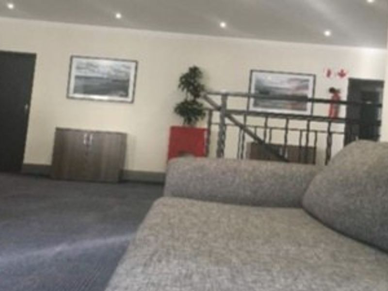 A commercial interior space featuring recessed downlighting, a metal balustrade, and carpeted flooring, suitable for a reception or waiting area.