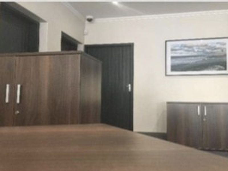 A functional office space featuring dark wood cabinetry, internal doors, and security camera installation, suitable for professional use.