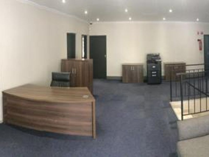 A commercial office space featuring recessed downlighting, carpeted flooring, and built-in cabinetry, with an adjacent staircase and railing.