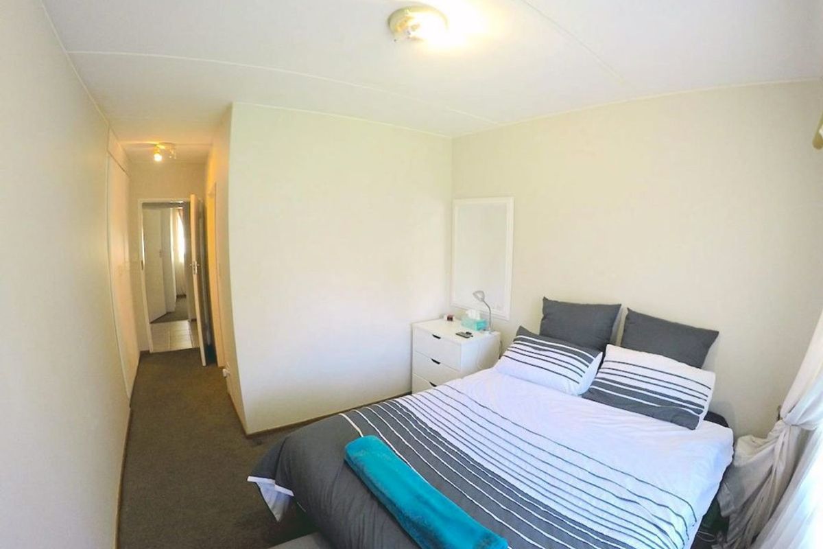 A functional bedroom featuring carpeted flooring, a built-in cupboard, and neutral wall finishes, providing a simple and practical living space.