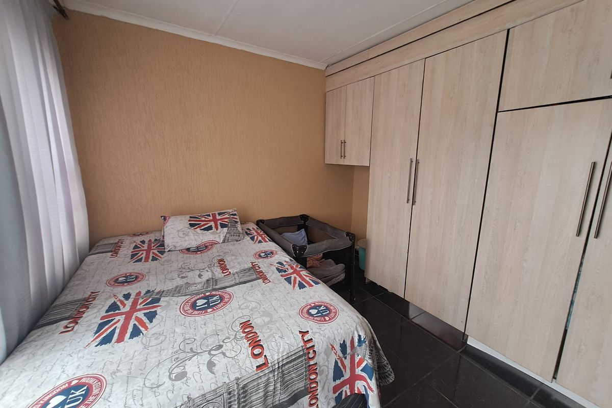 A bedroom featuring built-in wooden cupboards and dark tiled flooring, providing functional storage space.