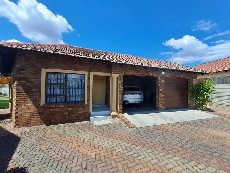 Front elevation of a face brick house featuring a double garage, paved driveway, and tiled roof.