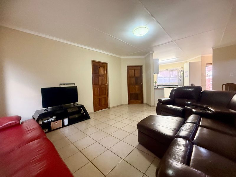 Open plan living area featuring tiled flooring, coved ceilings, and wooden panel doors, with a view through to the kitchen area.