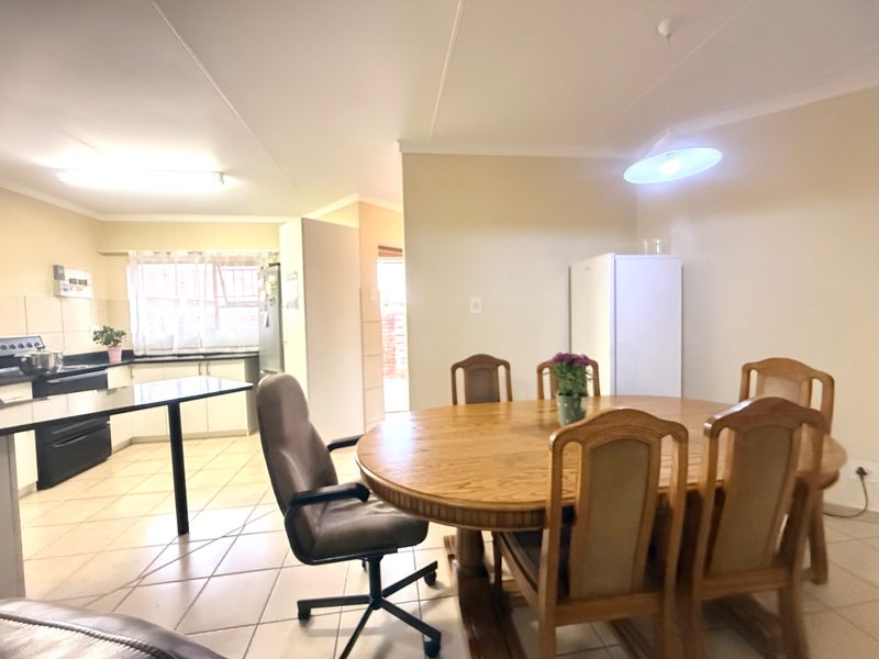 Open-plan living and dining area featuring tiled flooring, neutral walls, and a functional kitchen space with built-in cabinetry and countertops.