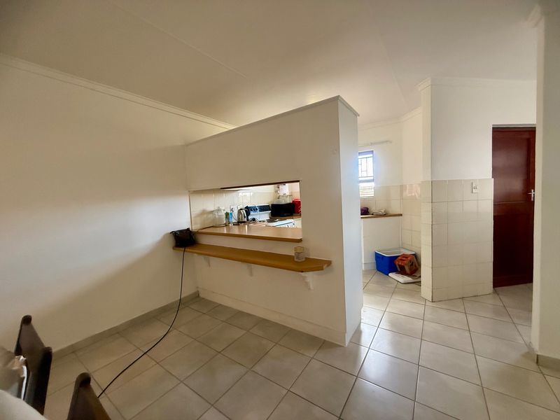 Open plan living area featuring a kitchen pass-through with a breakfast bar and tiled flooring throughout.