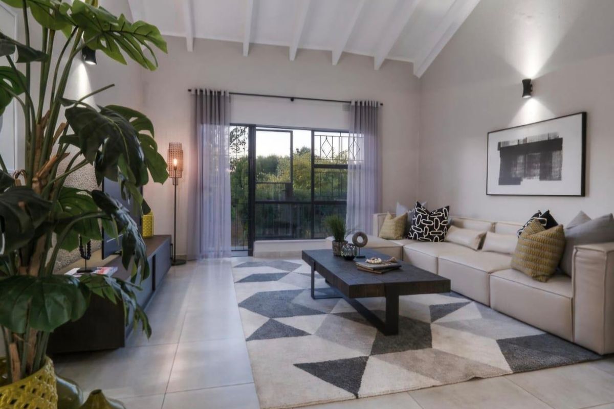 Spacious living room featuring a high vaulted ceiling with exposed rafters, tiled flooring, and a large sliding glass door providing natural light.