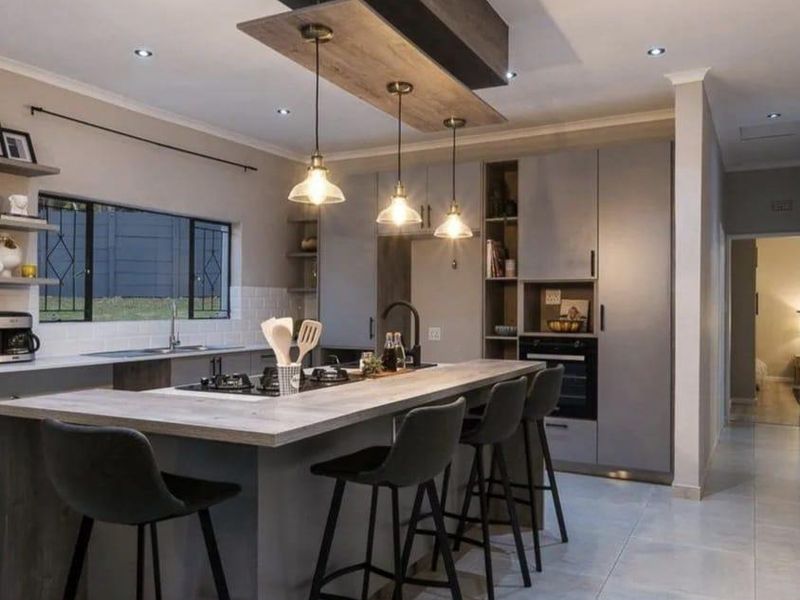 Modern kitchen featuring a central island with breakfast bar, built-in oven, gas hob, and contemporary cabinetry with integrated lighting.