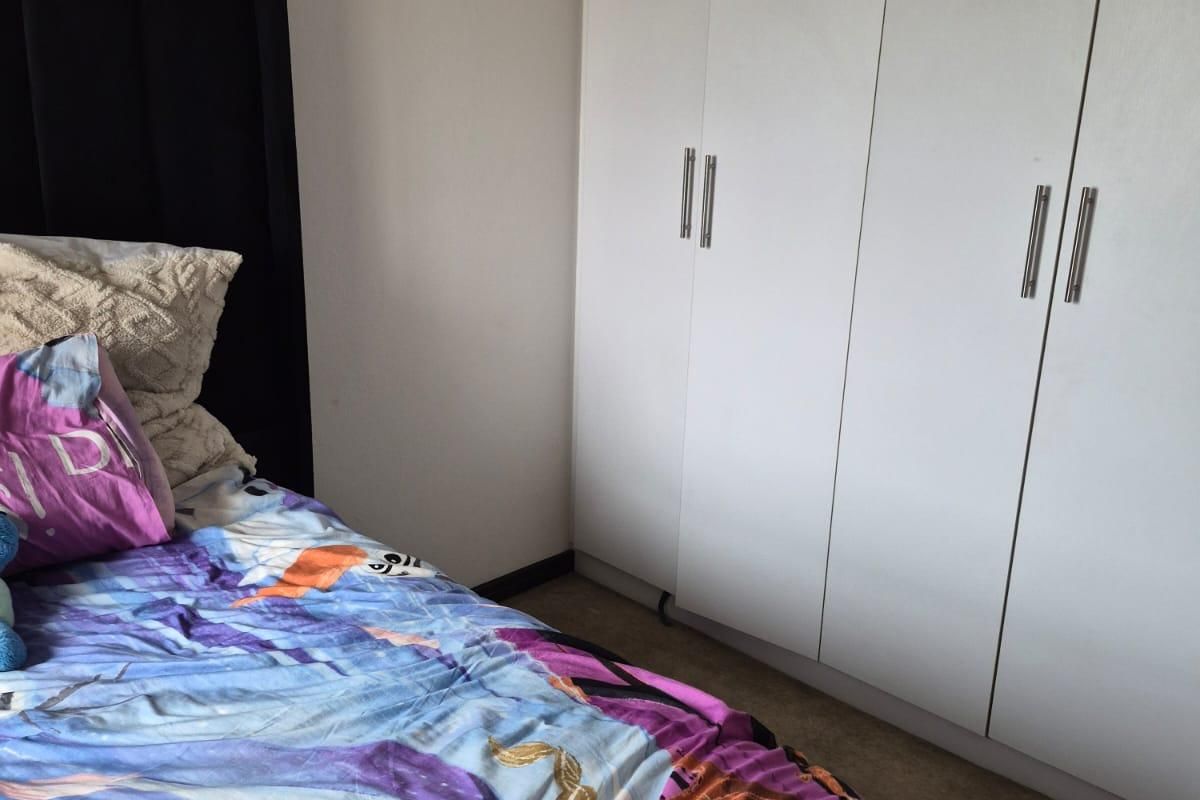 A bedroom featuring white built-in wardrobes with modern handles, providing ample storage space.