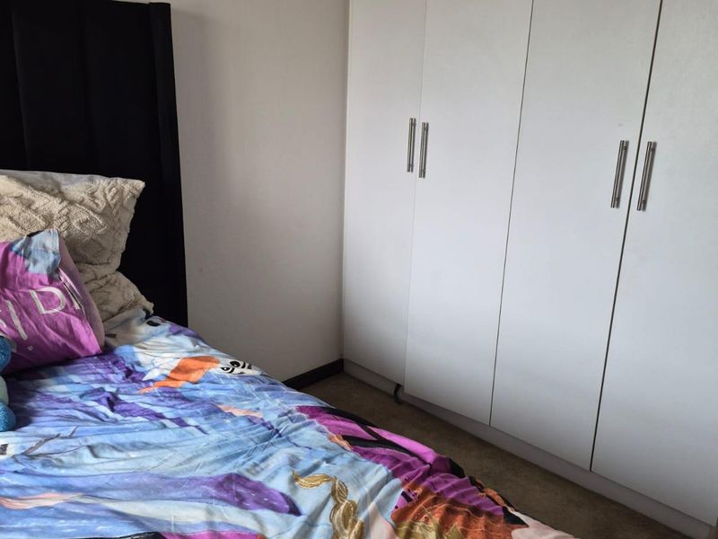 A bedroom featuring white built-in wardrobes with modern handles, providing ample storage space.