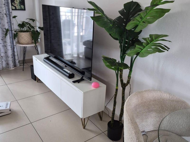 A bright living room area featuring neutral tiled flooring and clean wall finishes, providing a versatile space for relaxation.