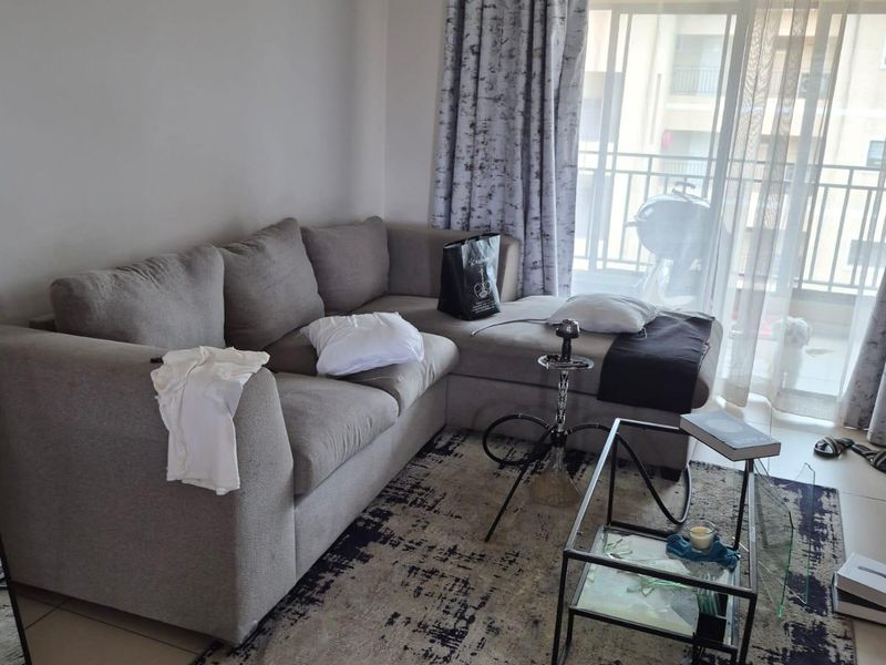 A living room area featuring tiled flooring and a sliding glass door leading to a balcony.