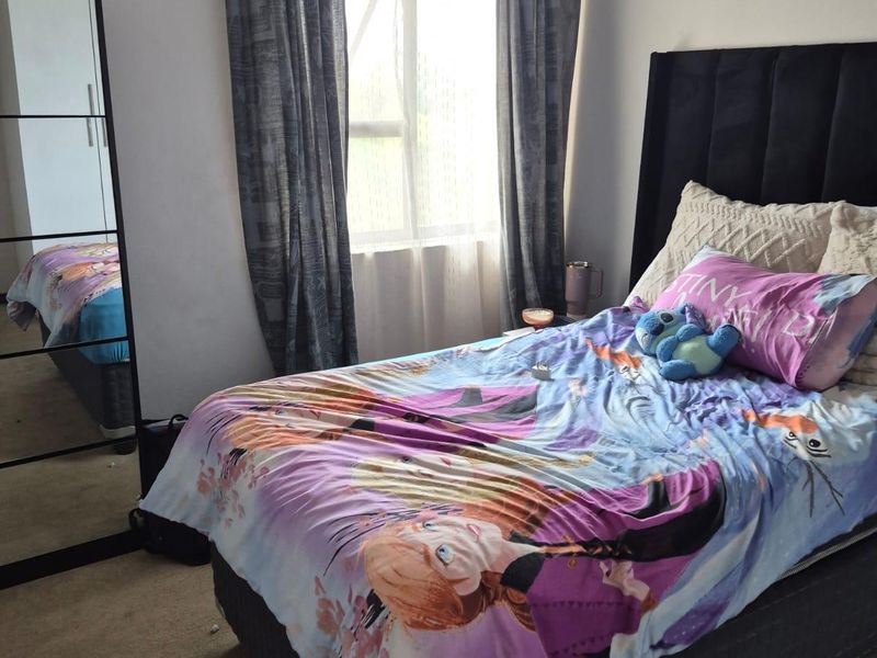 A standard bedroom featuring carpeted flooring and a window with installed curtain rods, providing a functional space for rest.
