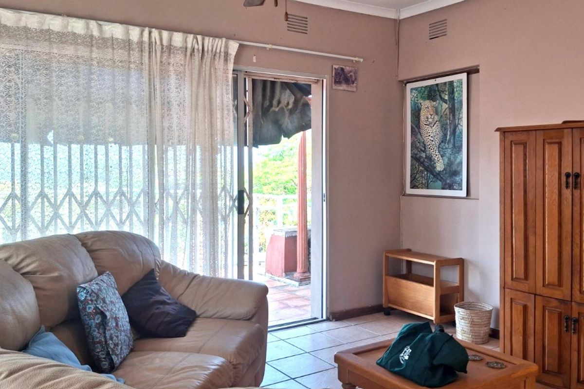 A living room featuring tiled flooring, a ceiling fan, and a sliding glass door providing access to an outdoor patio area.