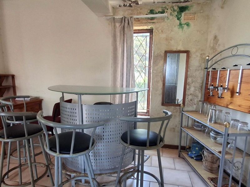 A dedicated bar area featuring tiled flooring and a window, currently showing significant wall damage and signs of moisture ingress requiring repair.