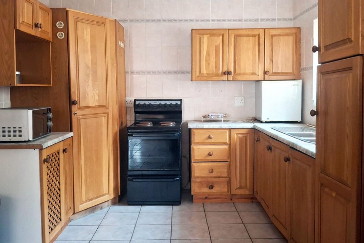 A functional kitchen featuring traditional wooden cabinetry, tiled backsplash, and a freestanding oven, offering a classic layout with ample storage space.