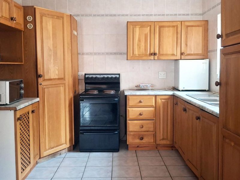 A functional kitchen featuring traditional wooden cabinetry, tiled backsplash, and a freestanding oven, offering a classic layout with ample storage space.