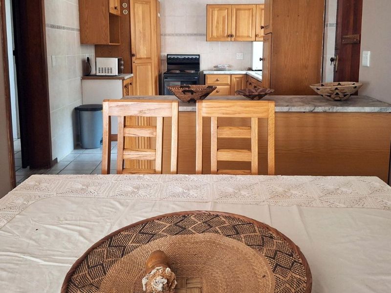 Open plan kitchen and dining area featuring wooden cabinetry, a breakfast bar, and tiled flooring.