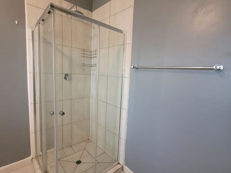 A functional bathroom featuring a corner shower enclosure with tiled surround and a wall-mounted towel rail.