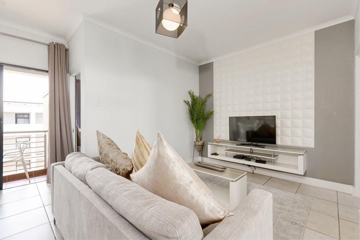 A bright and modern living room featuring tiled flooring, a textured feature wall, and a sliding glass door leading to an outdoor balcony.