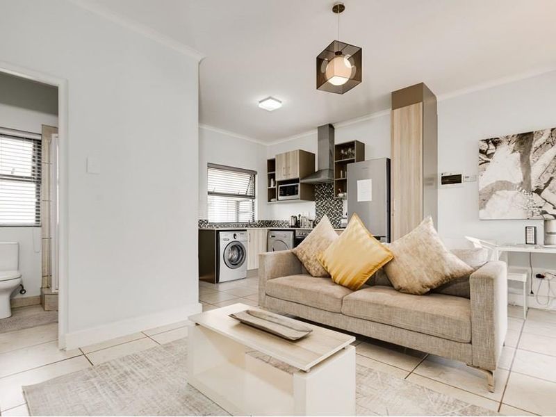 Open-plan living area featuring a modern kitchen with built-in cabinetry, tiled flooring, and an adjacent bathroom entrance.