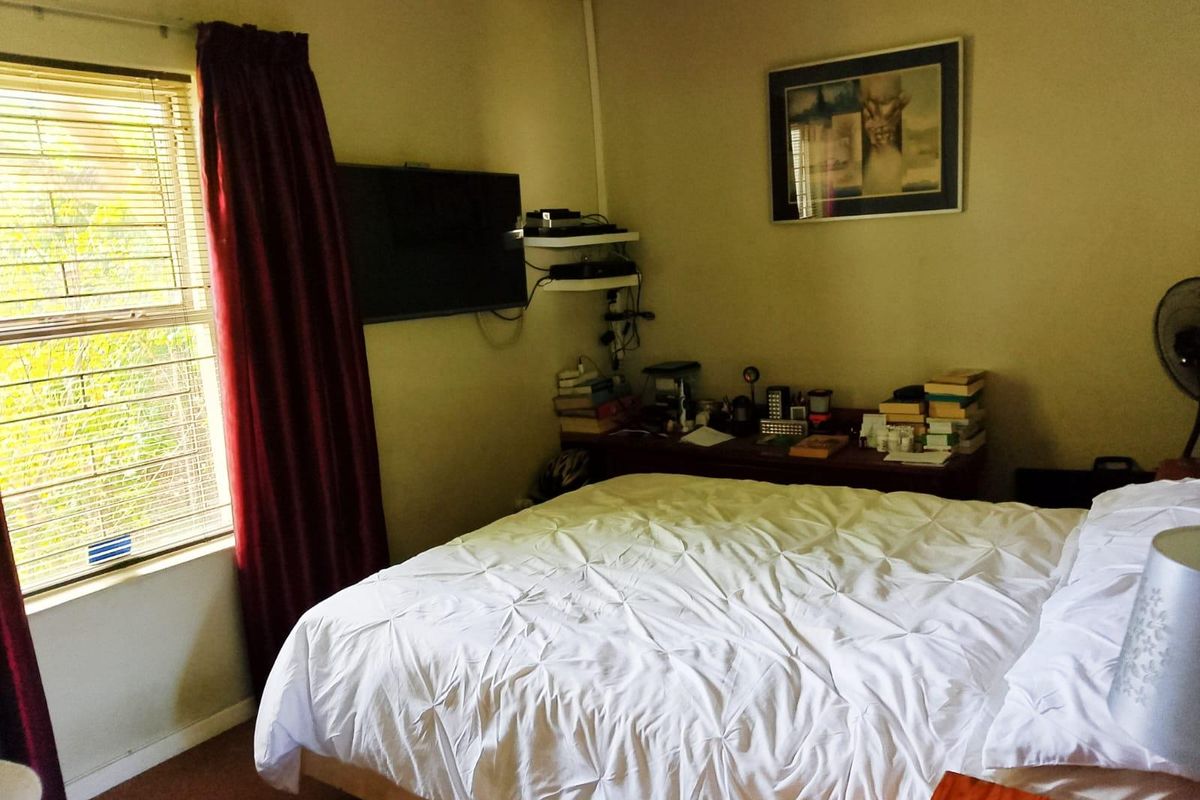 A standard bedroom featuring a window with security bars and coving detail.