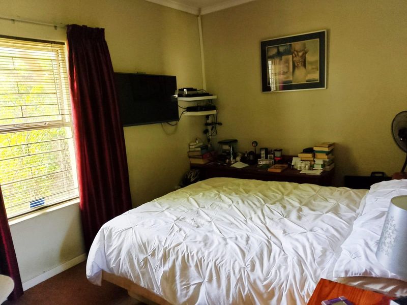 A standard bedroom featuring a window with security bars and coving detail.